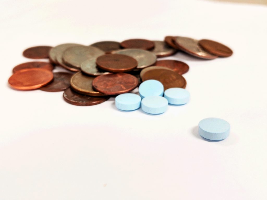 Pills and Coins on a white backdrop