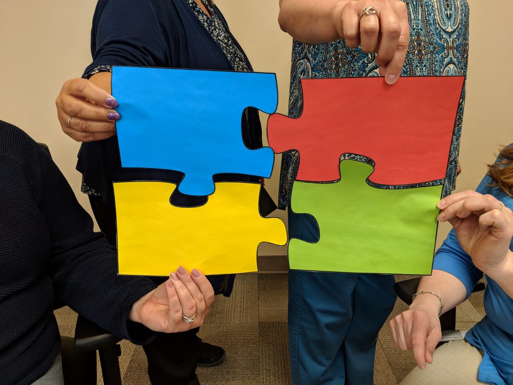 ATRIA team members holding puzzle pieces for autism awareness